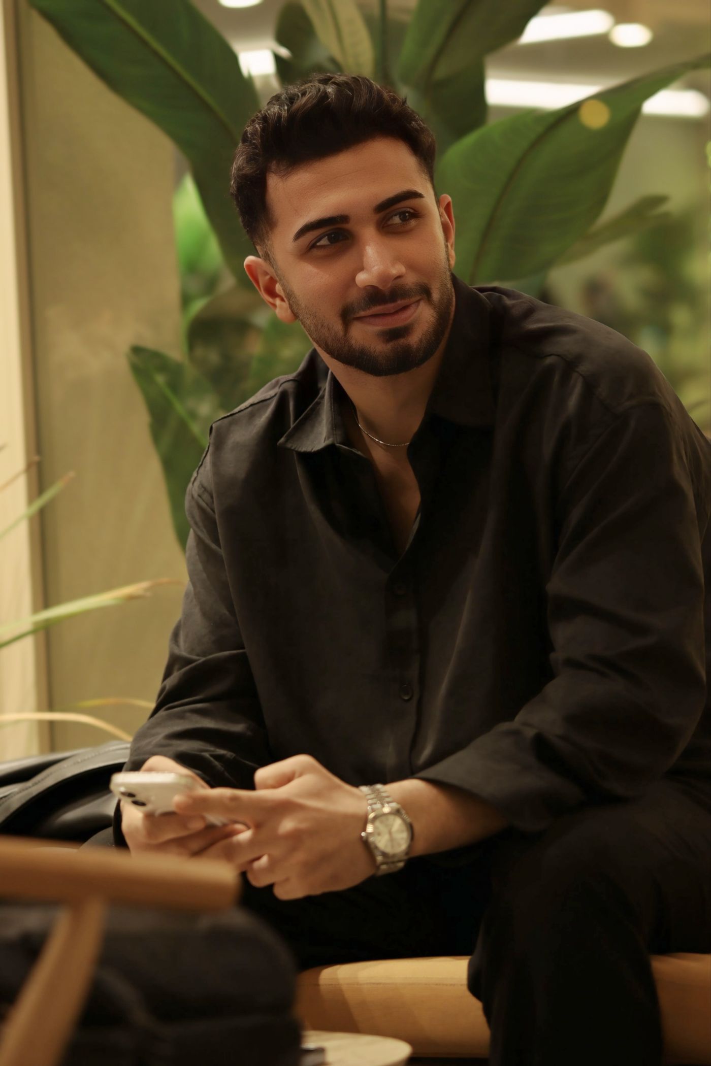 A man at a café smiling at his phone after paying